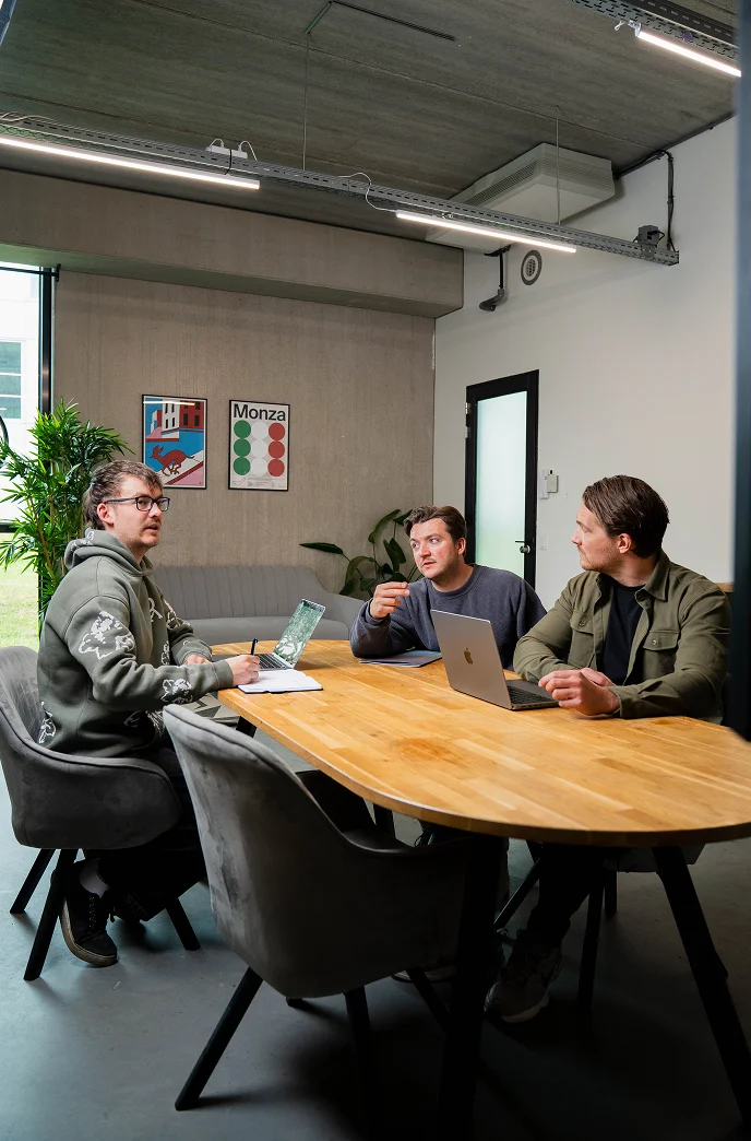 Toon, Vincent and Stijn from Brandbits are sitting at a table discussing a creative digital project together.