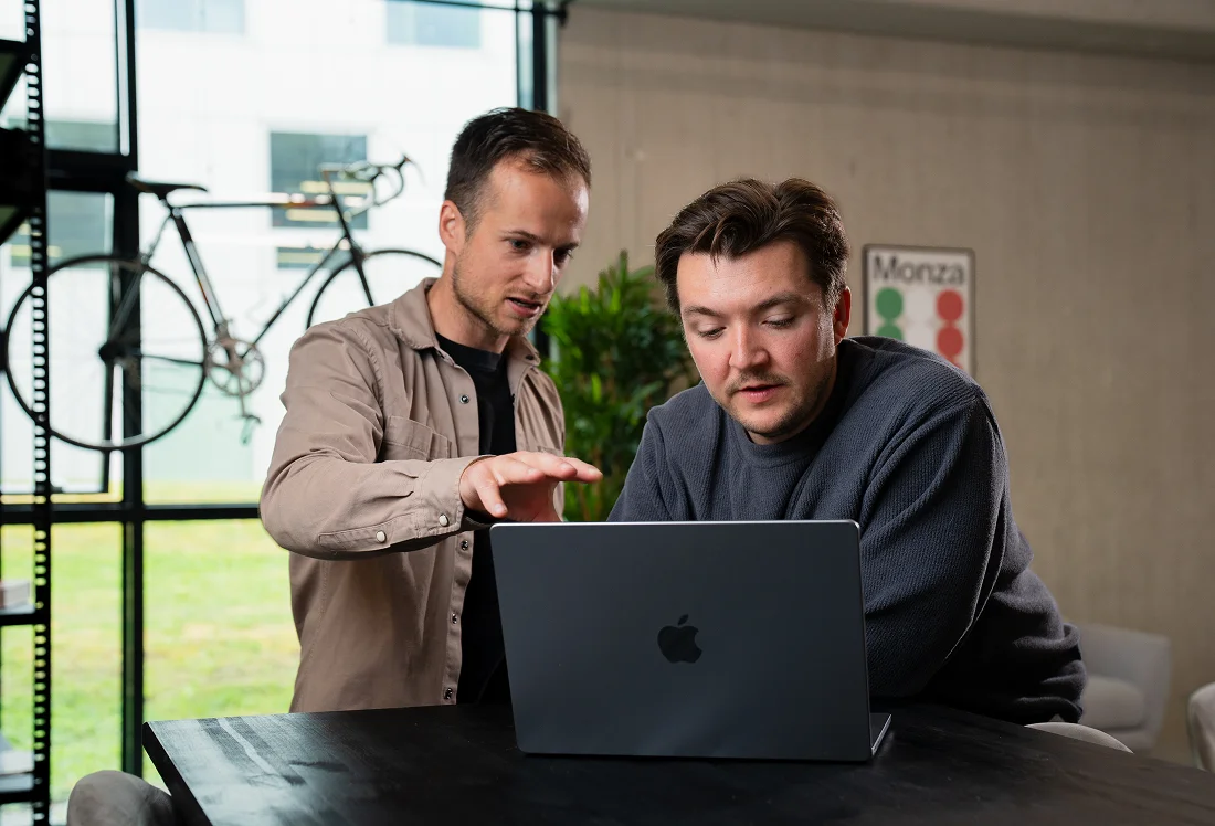 Two team members are working together on an employer branding presentation on a laptop.